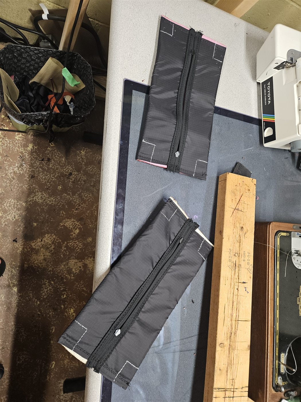Flat zipper panels laid out beside the sewing machine
